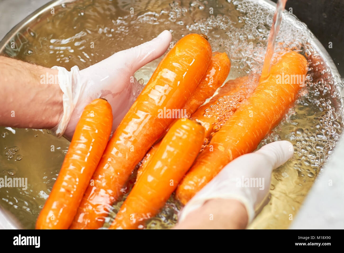 Lavado de manos Chef montón de zanahorias con agua corriente. Foto de stock