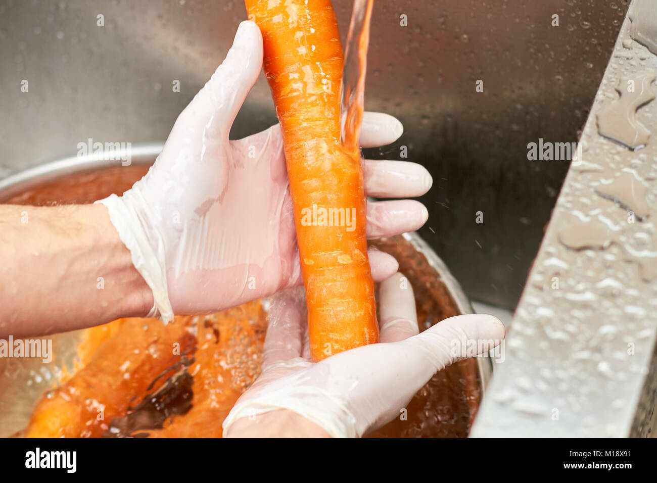 Una zanahoria de lavado con agua del grifo. Foto de stock