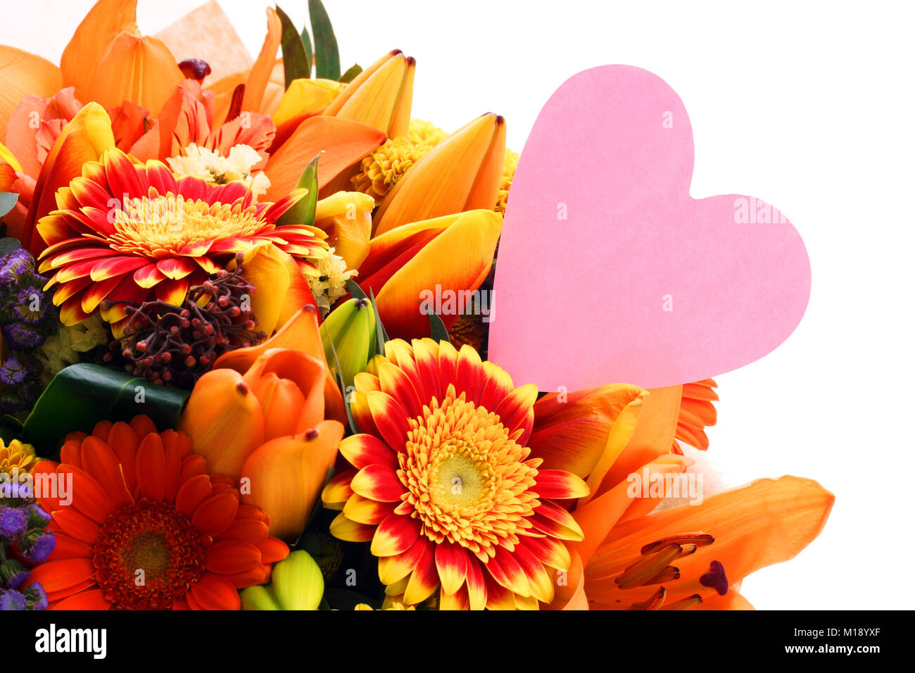 Ramo de flores con una nota en la forma de un corazón. Bouquet de flores de cerca, aislado sobre fondo blanco. Foto de stock