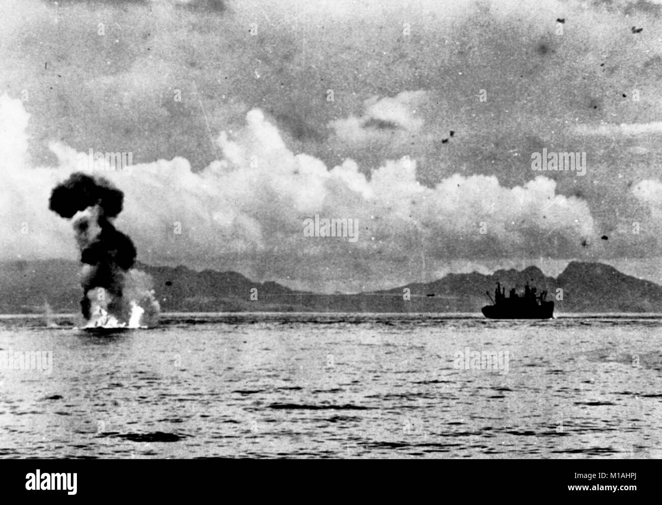 Un japonés Mitsubushi G4M "Betty" quemaduras de aeronaves en el agua después de que fue derribado por fuego antiaéreo durante un ataque contra Estados Unidos transporta entre Guadalcanal y Tulagi, 7-8 de agosto de 1942. Guadalcanal es en el fondo, con las alturas de Cabo Esperance a la derecha. Nota El G4M en vuelo por encima y a la izquierda del transporte. Foto de stock