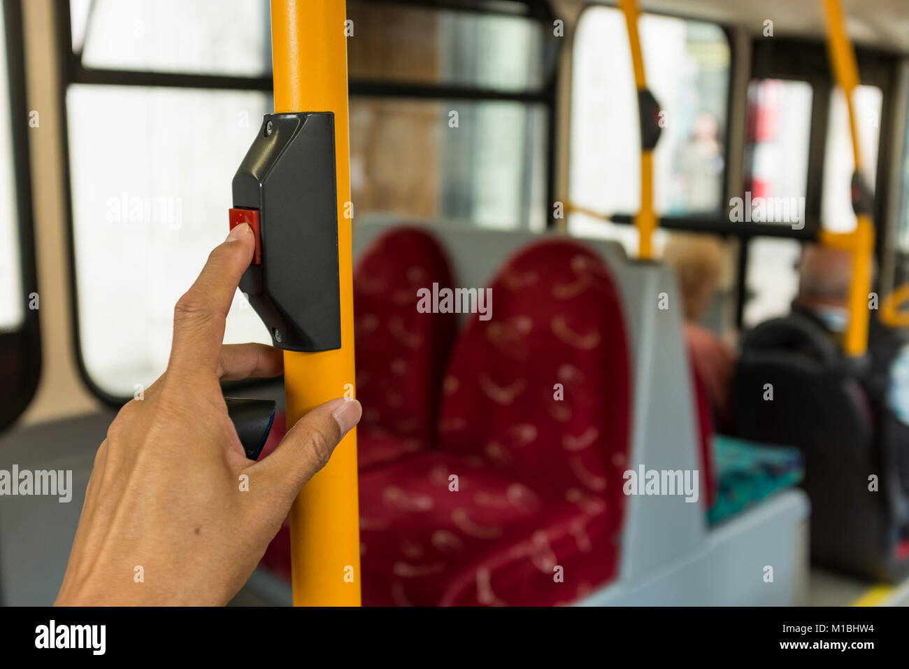 Un pasajero masculino está presionando el botón rojo de parada con su dedo índice en bus de Londres, Reino Unido Foto de stock