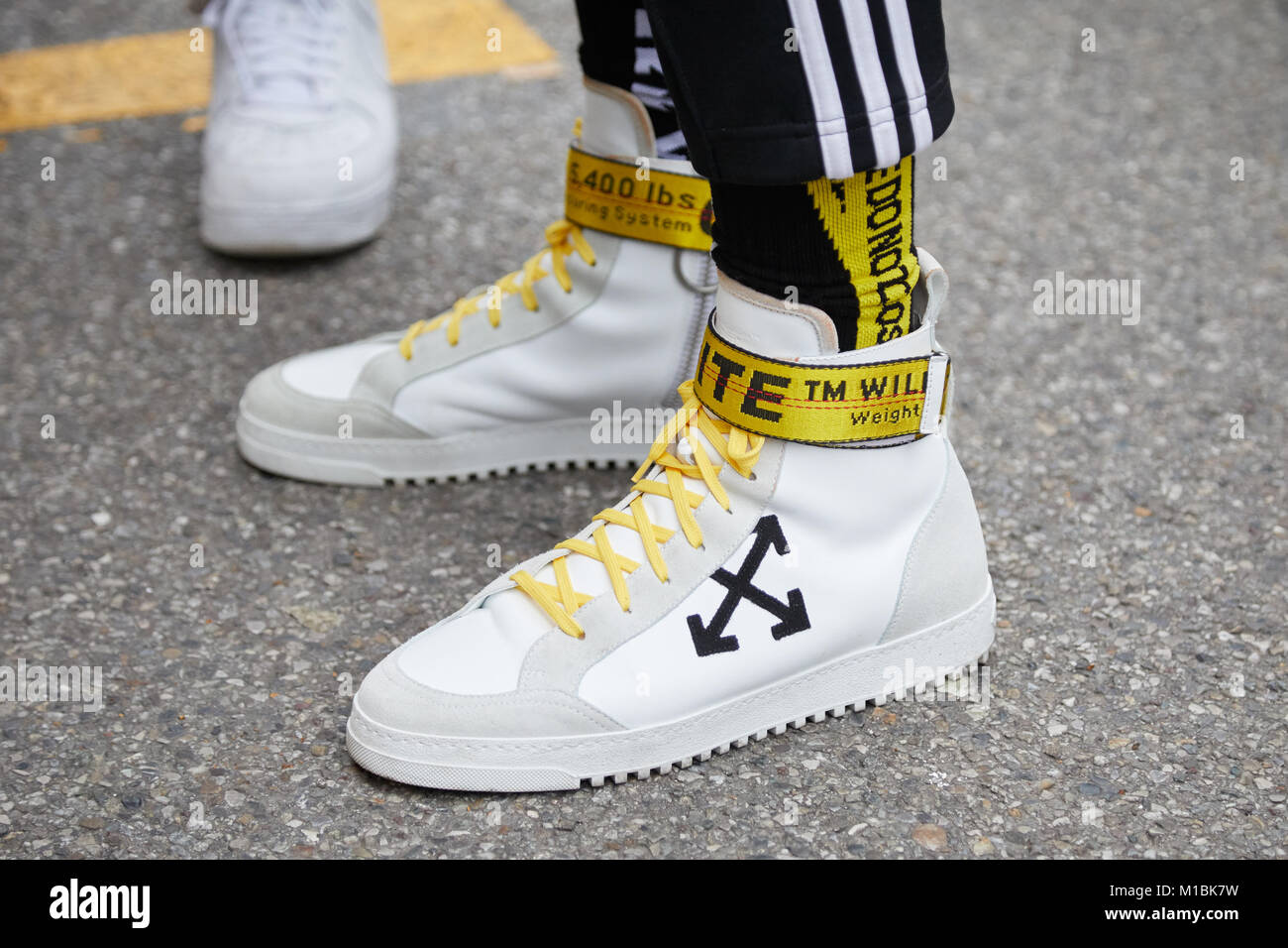 Milán - 15 de enero: el hombre con zapatillas blancas amarillo el cinturón de representar el Fashion Show, la Semana de la moda de Milán street style el de