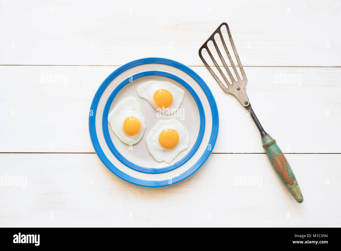 Huevos de codorniz frito sobre una placa cornishware con una espátula vintage desde arriba Foto de stock