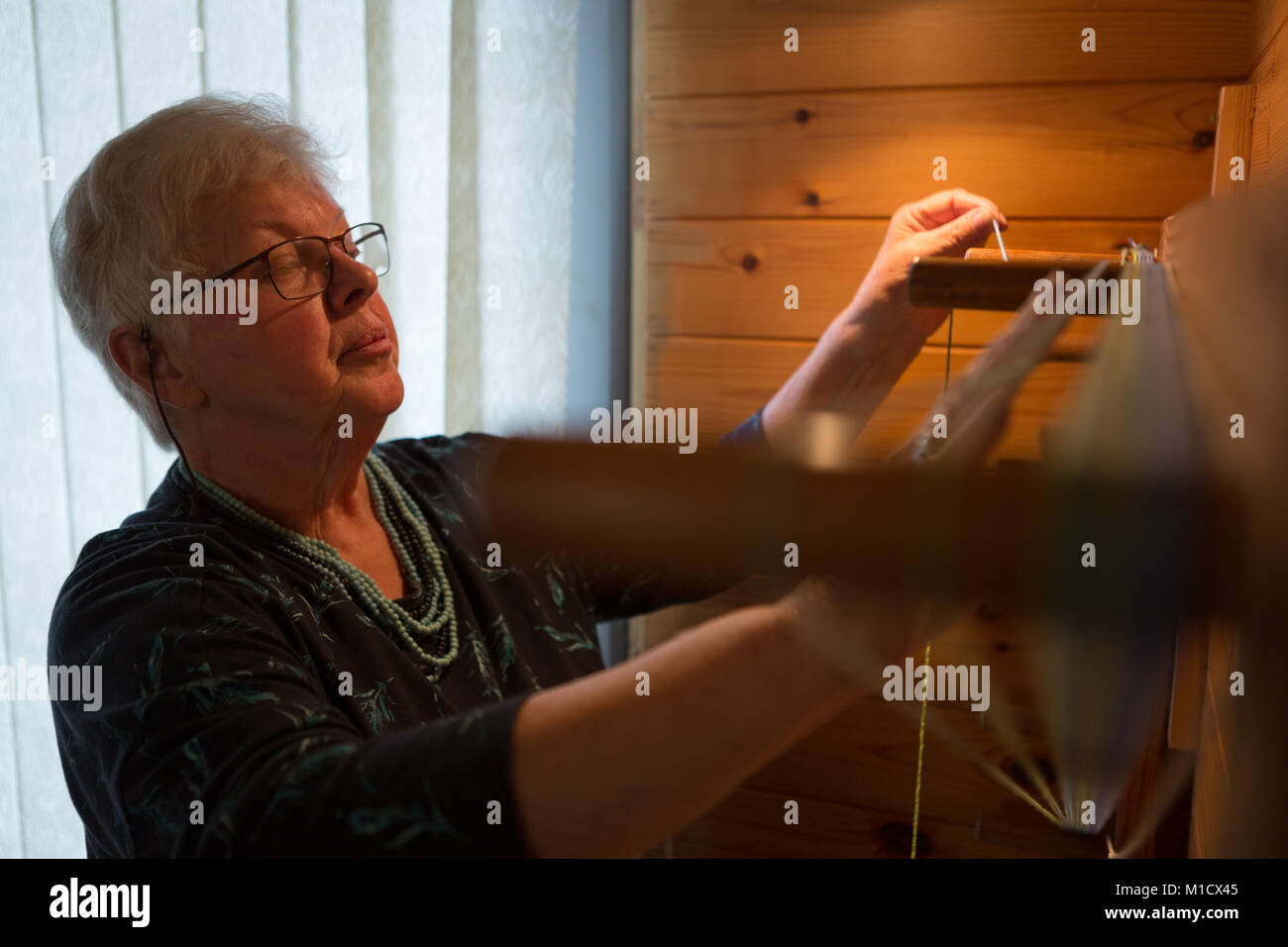 Mujer tejiendo seda senior en shop Foto de stock