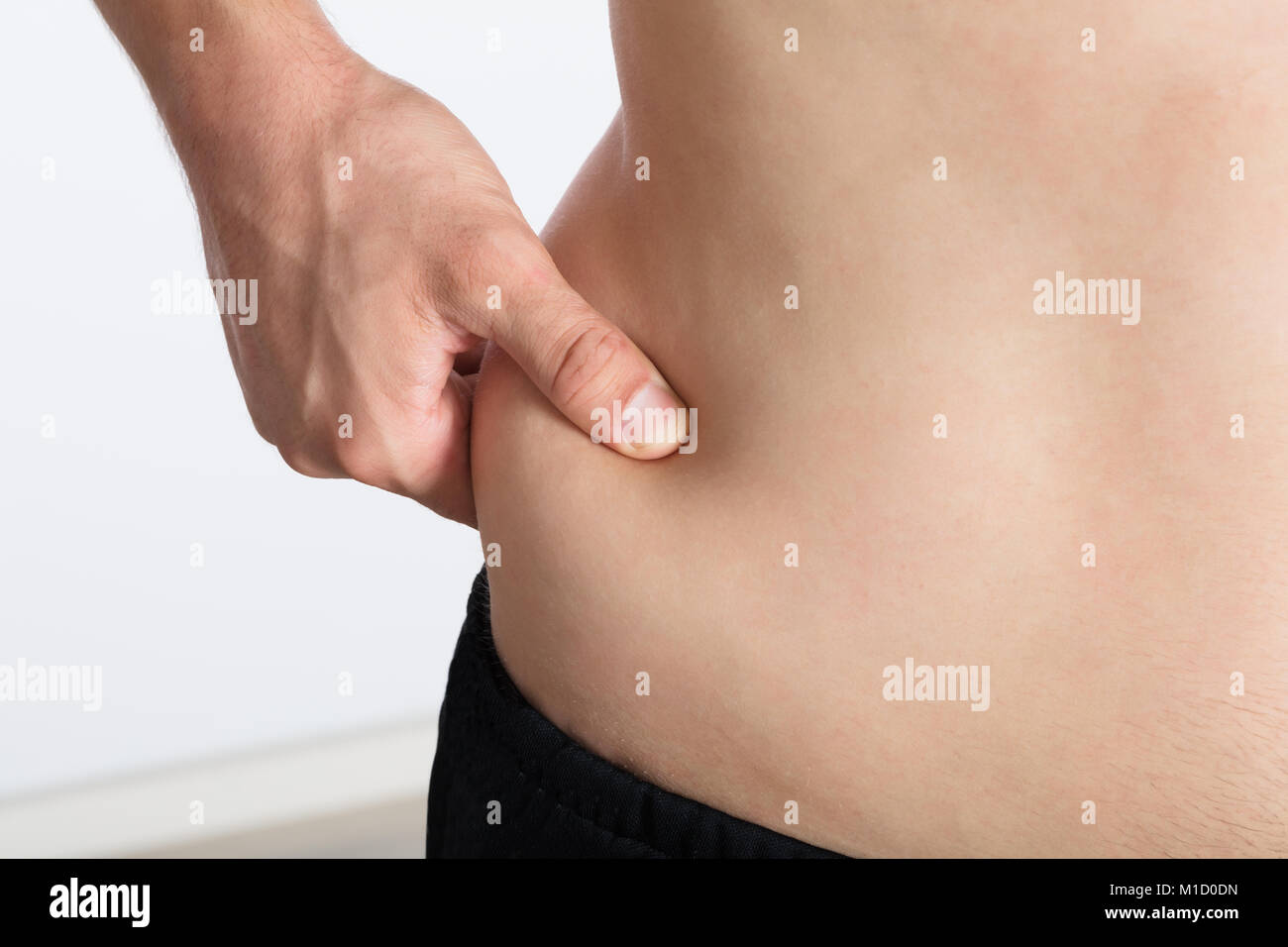 Close-up de la mano de una mujer aplastamiento excesivo de grasa en el estómago Foto de stock