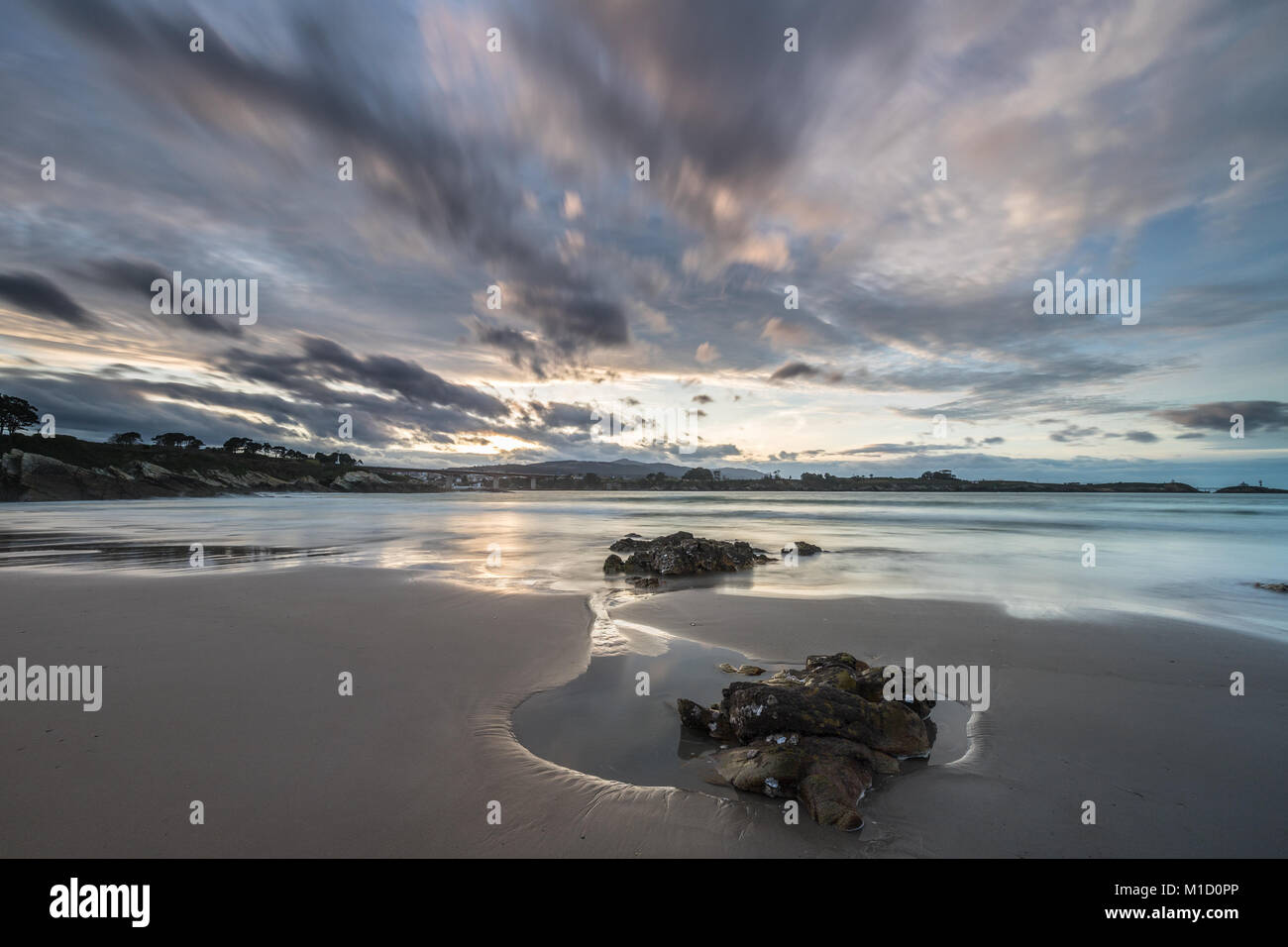 Espectacular atardecer en la playa de Arnao, Asturias, fotografías de los diferentes colores, formas y texturas de las nubes, se refleja en la fina arena Foto de stock
