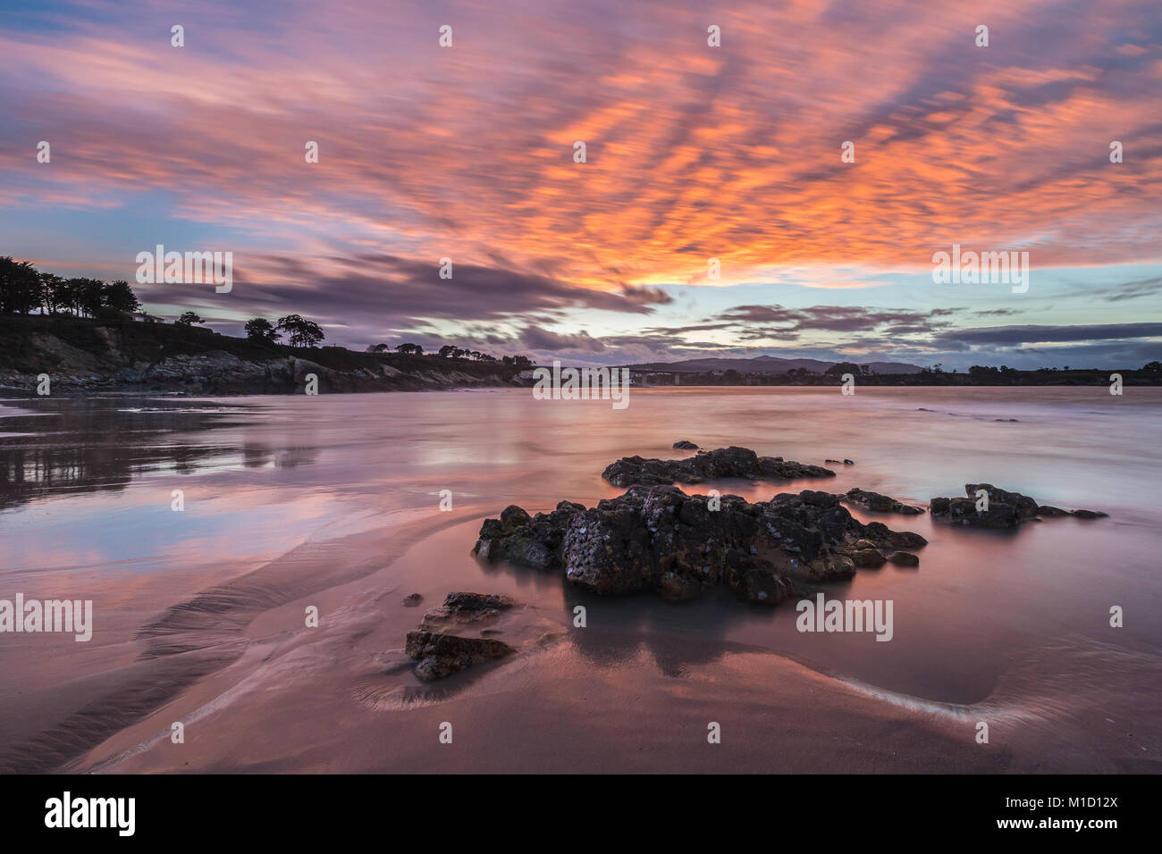 Espectacular atardecer en la playa de Arnao, Asturias, fotografías de los diferentes colores, formas y texturas de las nubes, se refleja en la fina arena Foto de stock