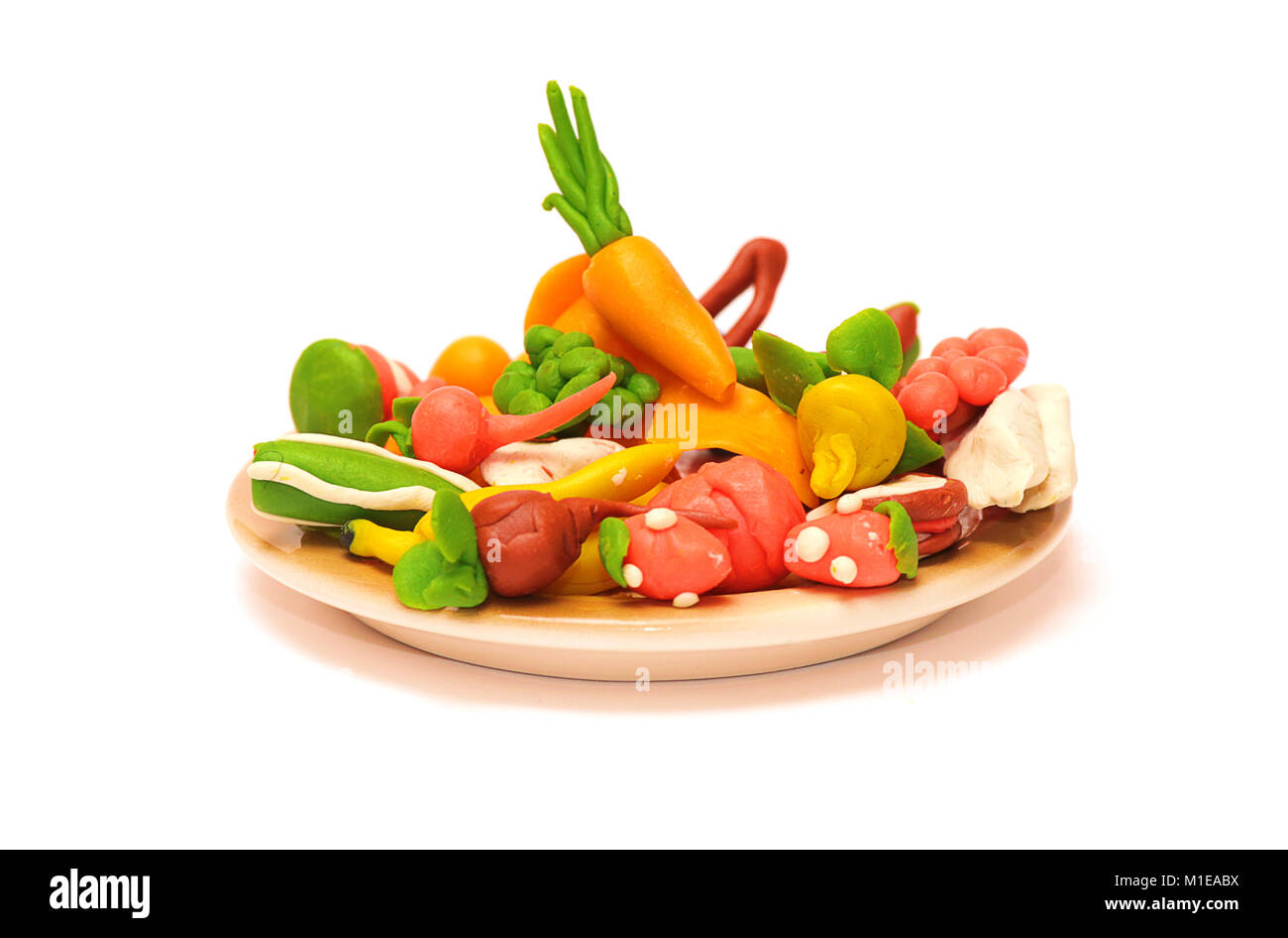 Plastilina verduras y frutas en un plato sobre un fondo blanco. Foto de stock