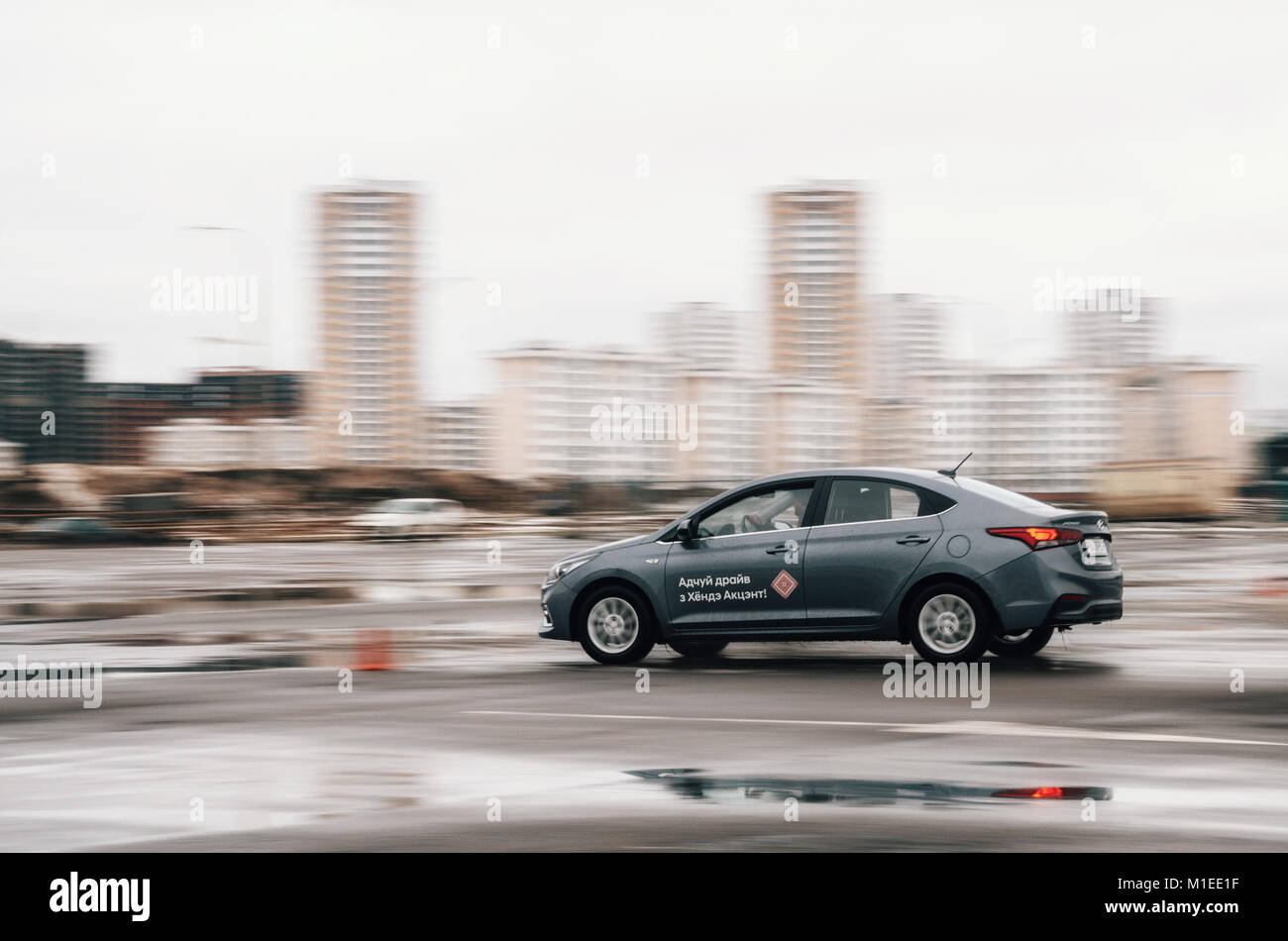 Minsk, Belarus, 29 de enero de 2018 movimiento borrosa. Hyundai Accent o Solaris coche se mueve muy rápida velocidad en pista con charcos en días nublados Foto de stock