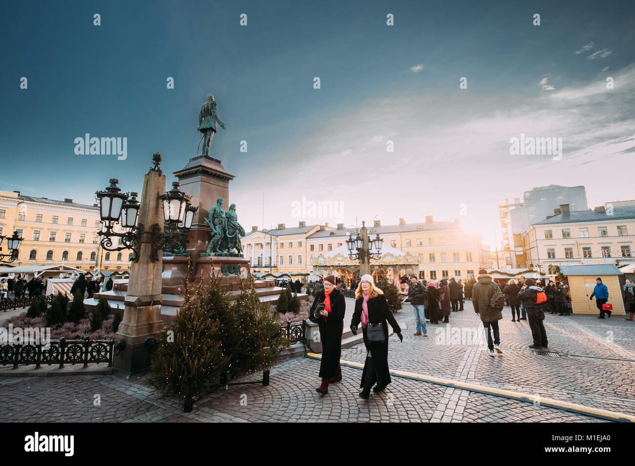 Helsinki, Finlandia - 10 de diciembre de 2016: Dos mujeres gente caminando cerca del monumento al emperador ruso Alejandro II en la Plaza del Senado en invierno soleado Christm Foto de stock