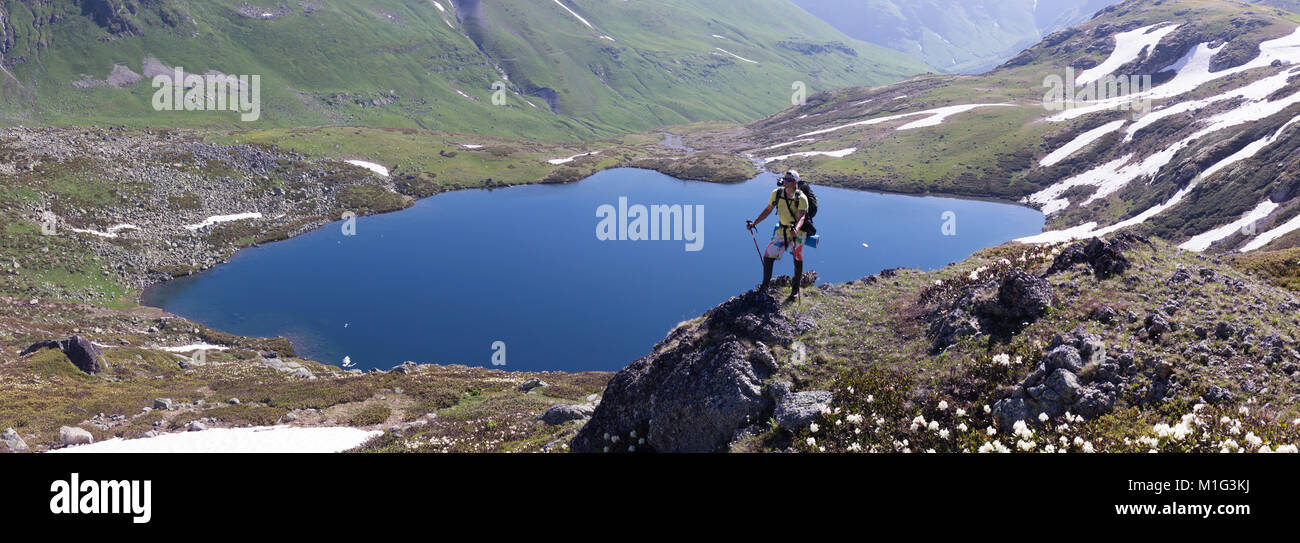 Un viajero en las montañas contra el telón de fondo de paisajes idílicos de praderas alpinas con un lago. Estilo de vida es activo, senderismo, turismo. Picturesqu Foto de stock