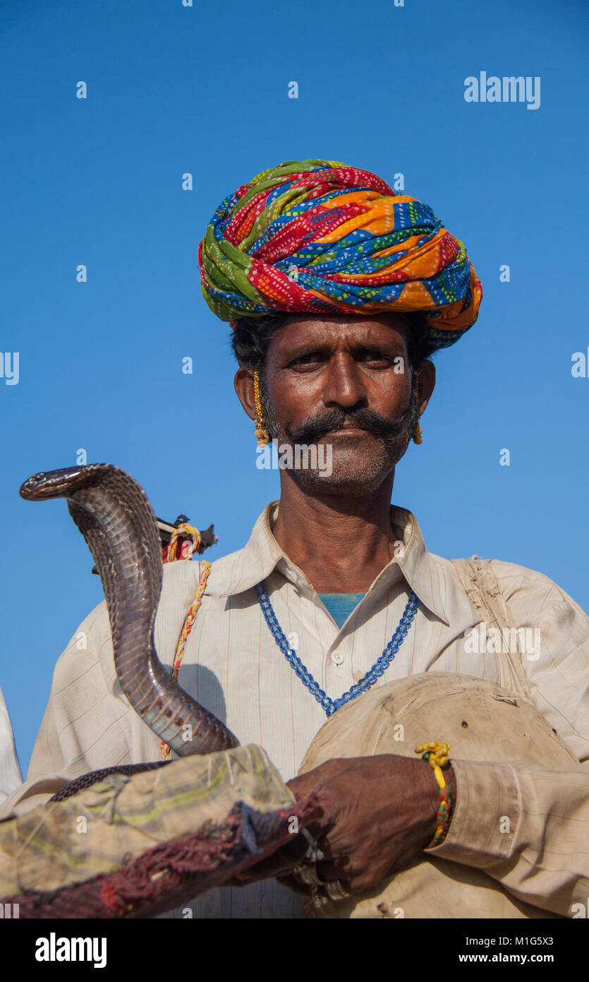 Encantador de serpientes con una cobra para entretener a los turistas por dinero en la Feria de camellos de Pushkar, Rajastán, India Foto de stock