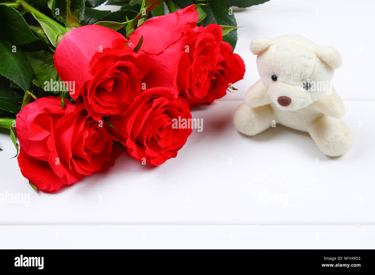 Oso de peluche blanco rodeado de rosas rosas sobre una mesa de madera  blanca. Plantilla para el 8 de marzo, Día de la Madre, Día de San Valentín  Fotografía de stock - Alamy