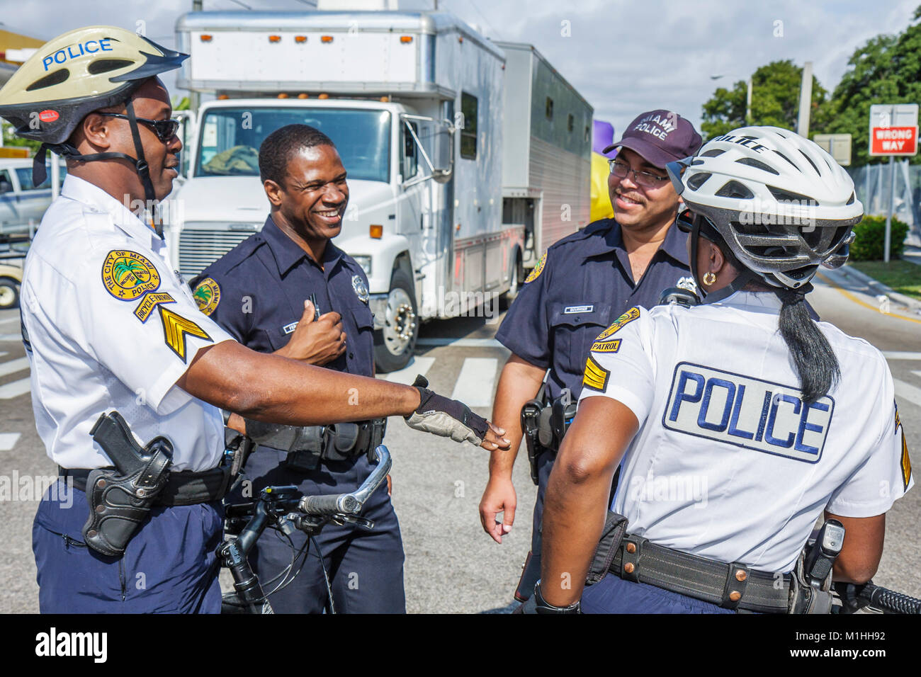 Miami Florida, Little Havana, Calle Ocho, policía, bicicleta, ciclismo, montar, ciclismo, jinete, patrulla de bicicleta, ocupación, protección, pistola, aplicación de la ley, negros negros Foto de stock