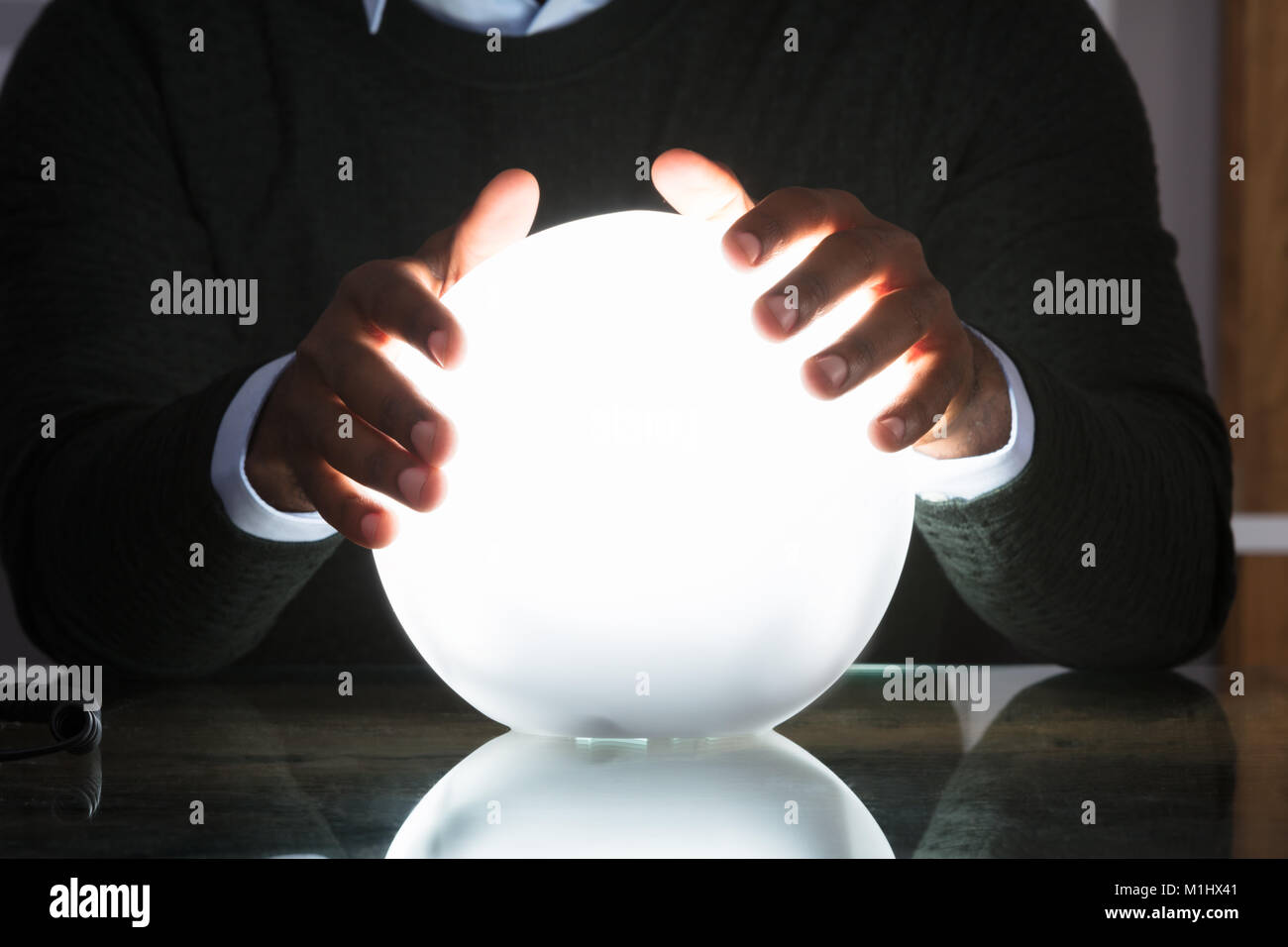 Cerca del empresario con las manos en la bola de cristal en el escritorio en la oficina Foto de stock