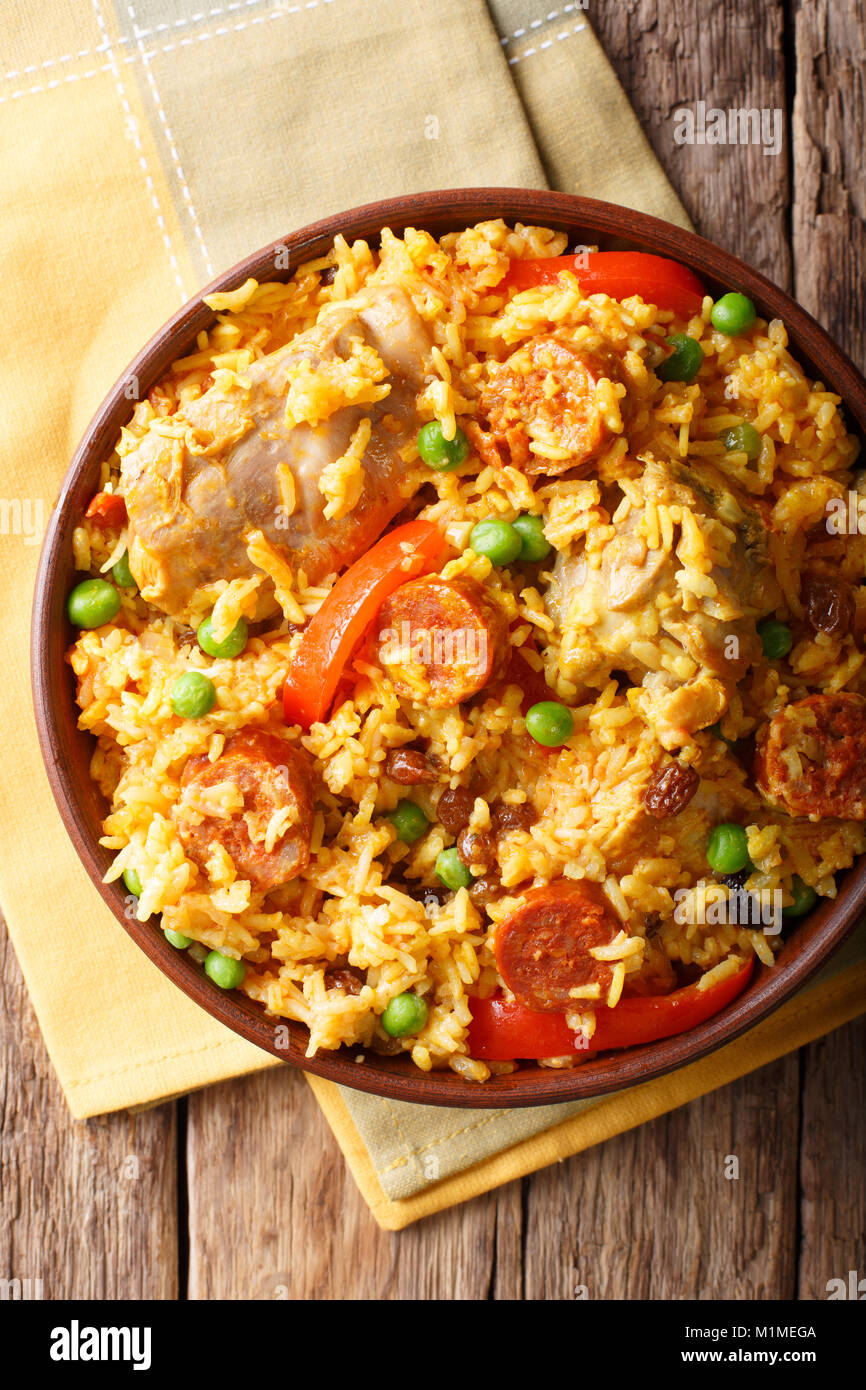 Valenciana Arroz con conejo, chorizo, hortalizas y especias en un recipiente sobre la mesa. vertical superior vista desde arriba Foto de stock