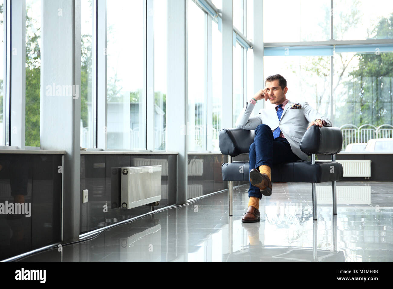 Un ángulo bajo la foto de un apuesto joven empresario en un moderno espacio de oficina con grandes ventanales. Foto de stock