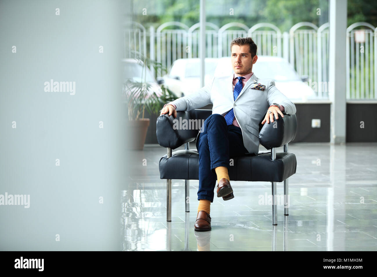 Un ángulo bajo la foto de un apuesto joven empresario en un moderno espacio de oficina con grandes ventanales. Foto de stock