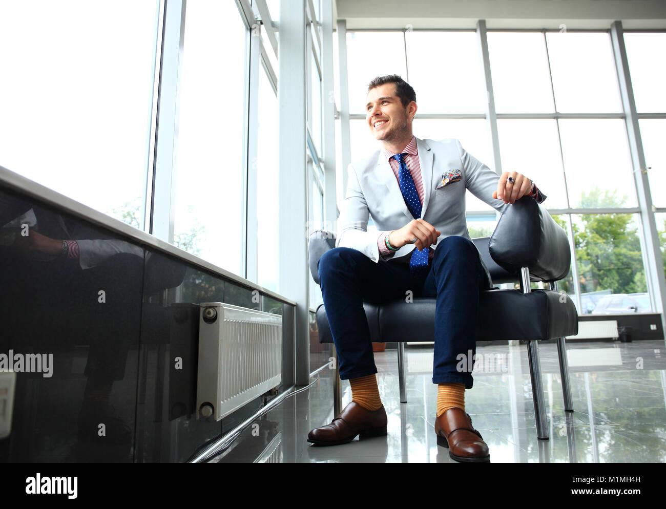 Un ángulo bajo la foto de un apuesto joven empresario en un moderno espacio de oficina con grandes ventanales. Foto de stock