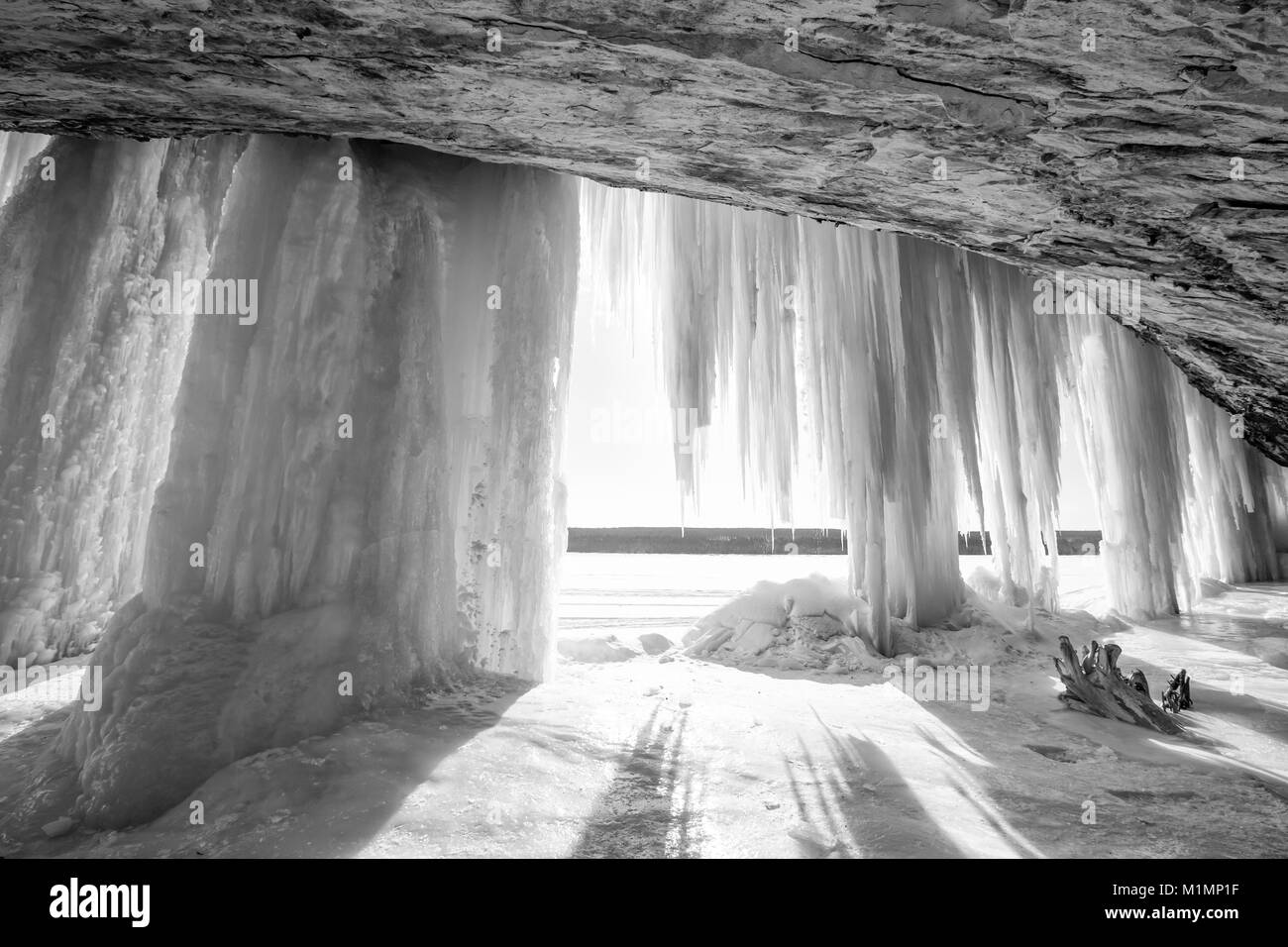 Una explosión de sol brilla alrededor de una columna de hielo cortina en Grand Island cerca de Munising Michigan en invierno Foto de stock