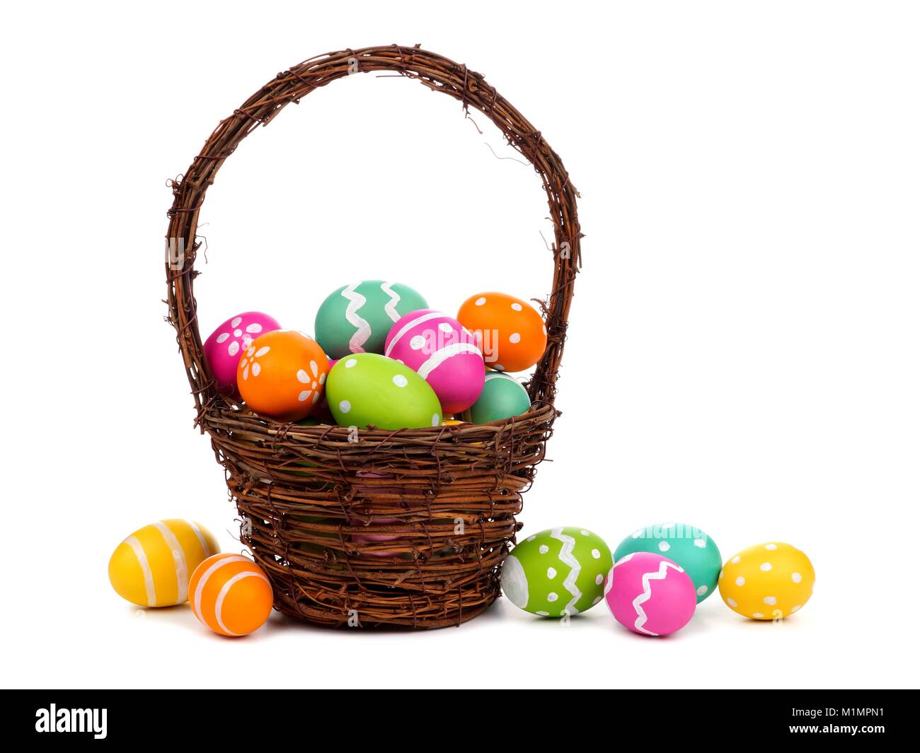 Canasta de Pascua llena de coloridos Huevos de Pascua pintados a mano sobre un fondo blanco. Foto de stock