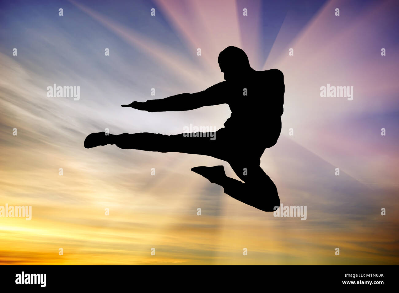 Silueta de à hombre volando patada en el cielo del atardecer de fondo. Composición de artes marciales. Foto de stock