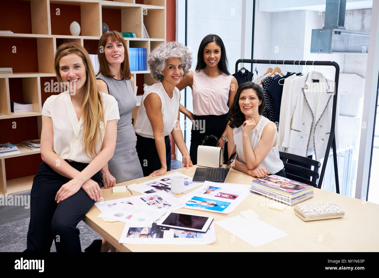Todo el equipo creativo femenino sonriendo a la cámara en una oficina. Foto de stock