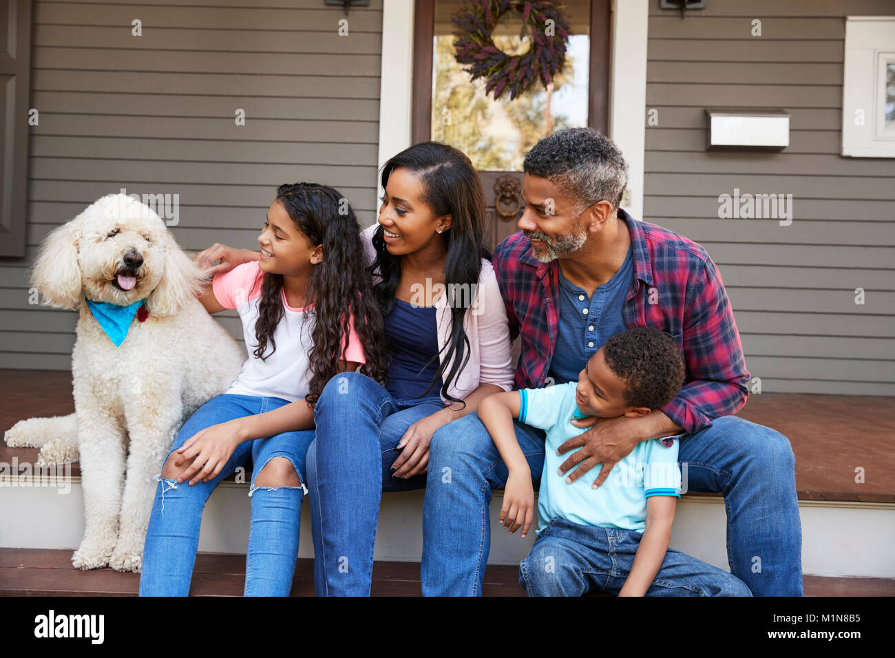 Familia con niños y perro mascota sentarse sobre los pasos de inicio Foto de stock