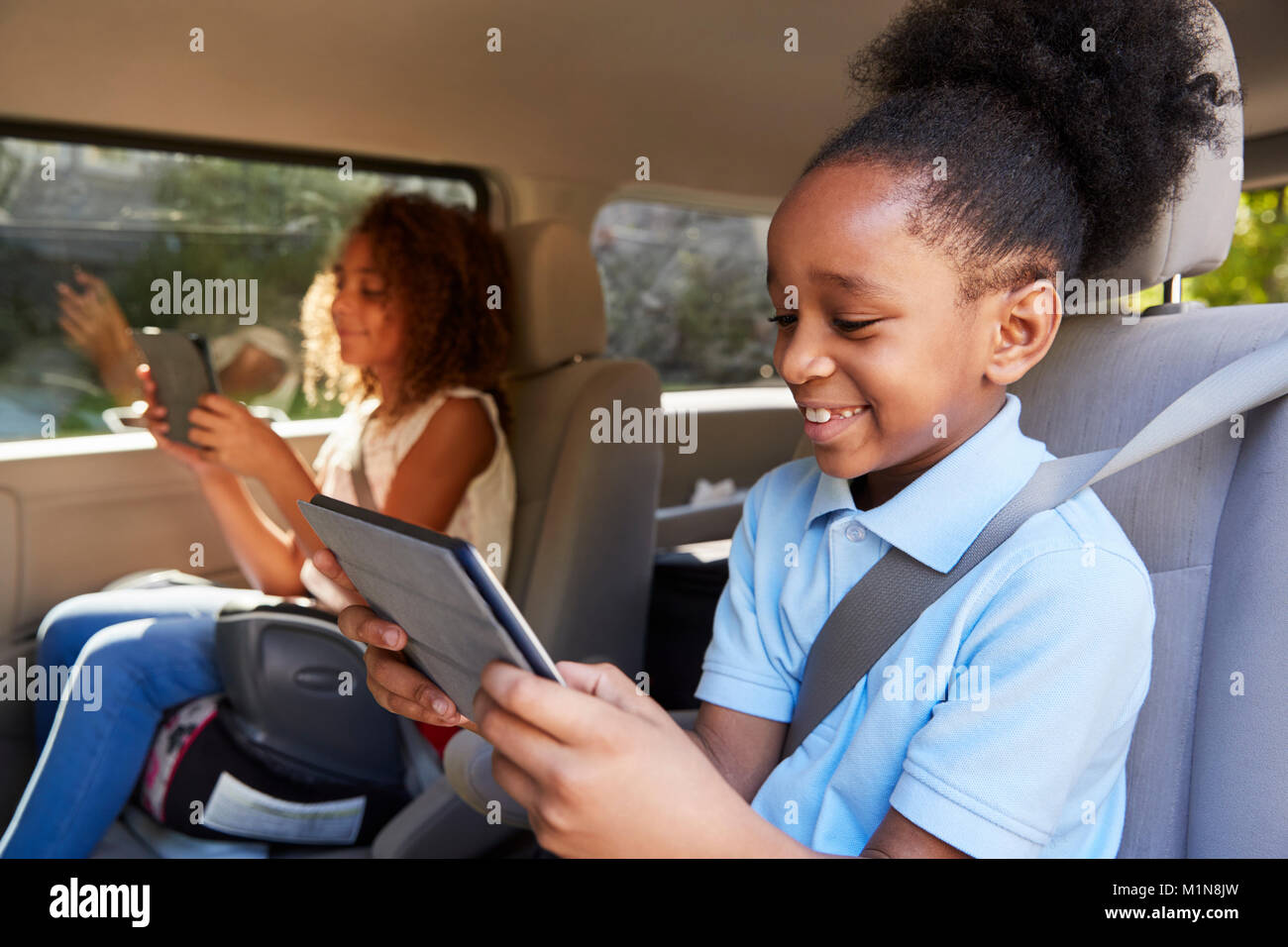 Los niños utilizando dispositivos digitales en un trayecto en coche Foto de stock