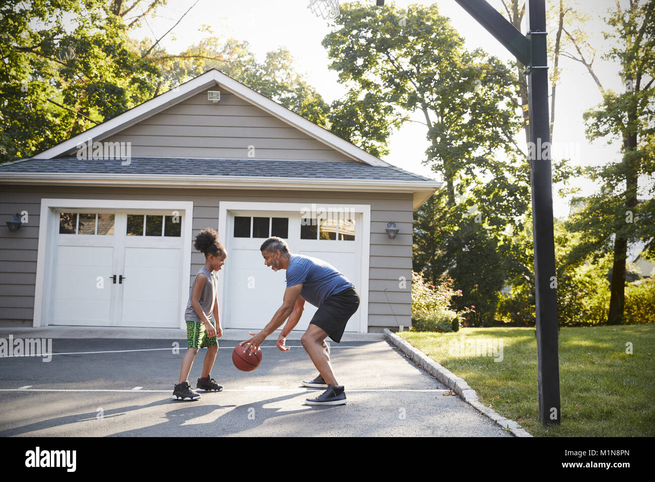 Padre e hijo jugando básquetbol en camino a casa Foto de stock