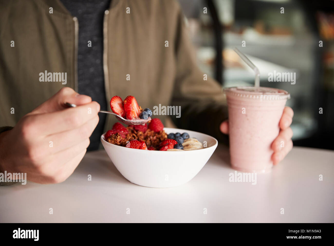 Cerca de hombre comiendo saludable desayuno de granola en Cafe Foto de stock