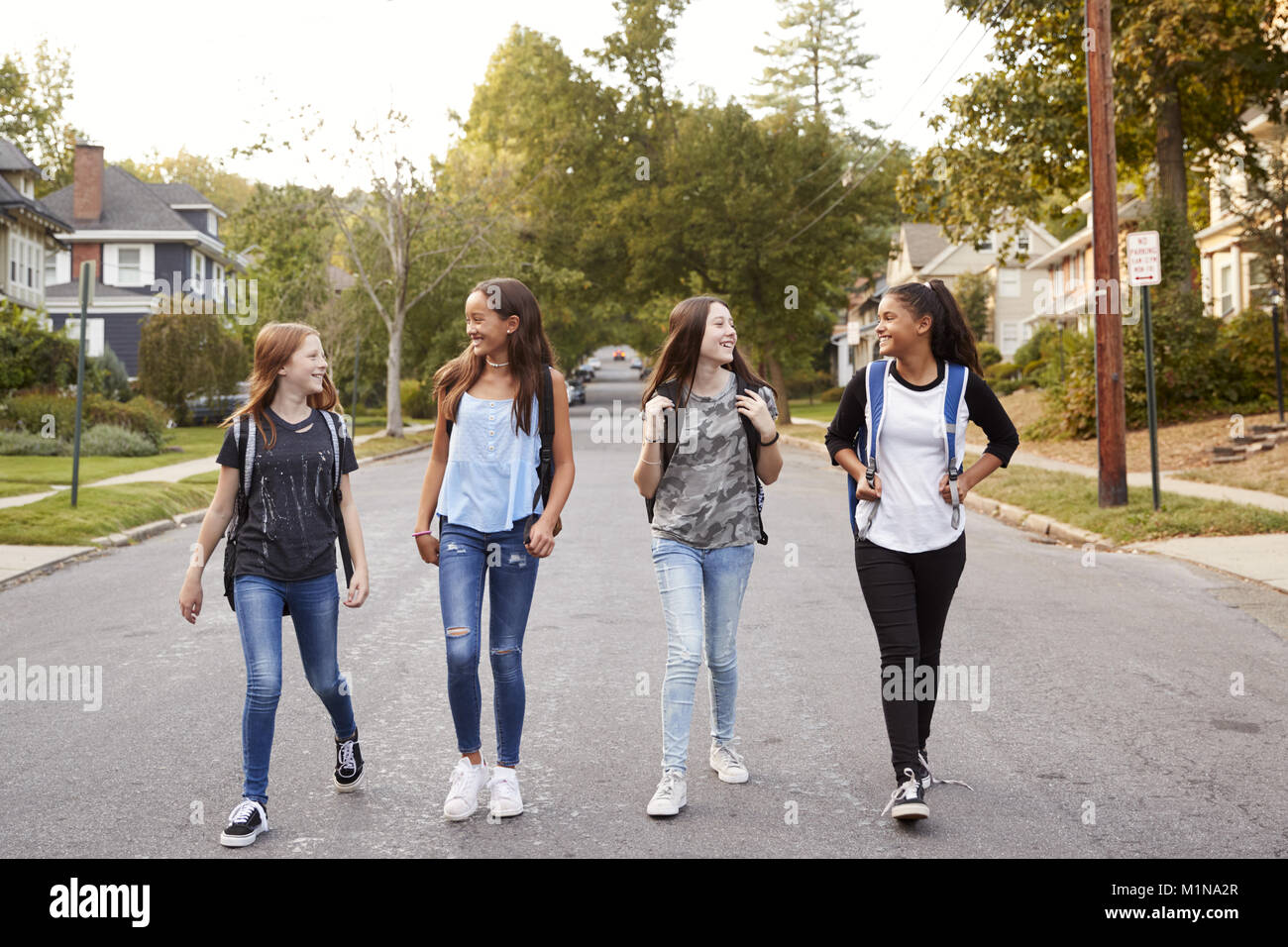 Cuatro jóvenes adolescentes caminando por la carretera, longitud completa Foto de stock