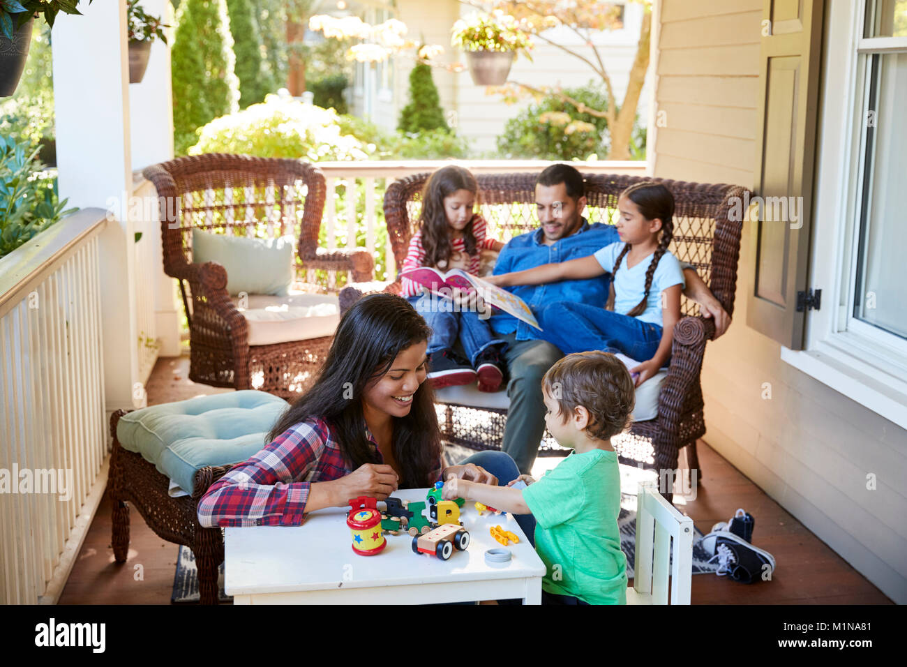 Sentarse en el porche de la familia de la casa de libros de lectura y juegos. Foto de stock