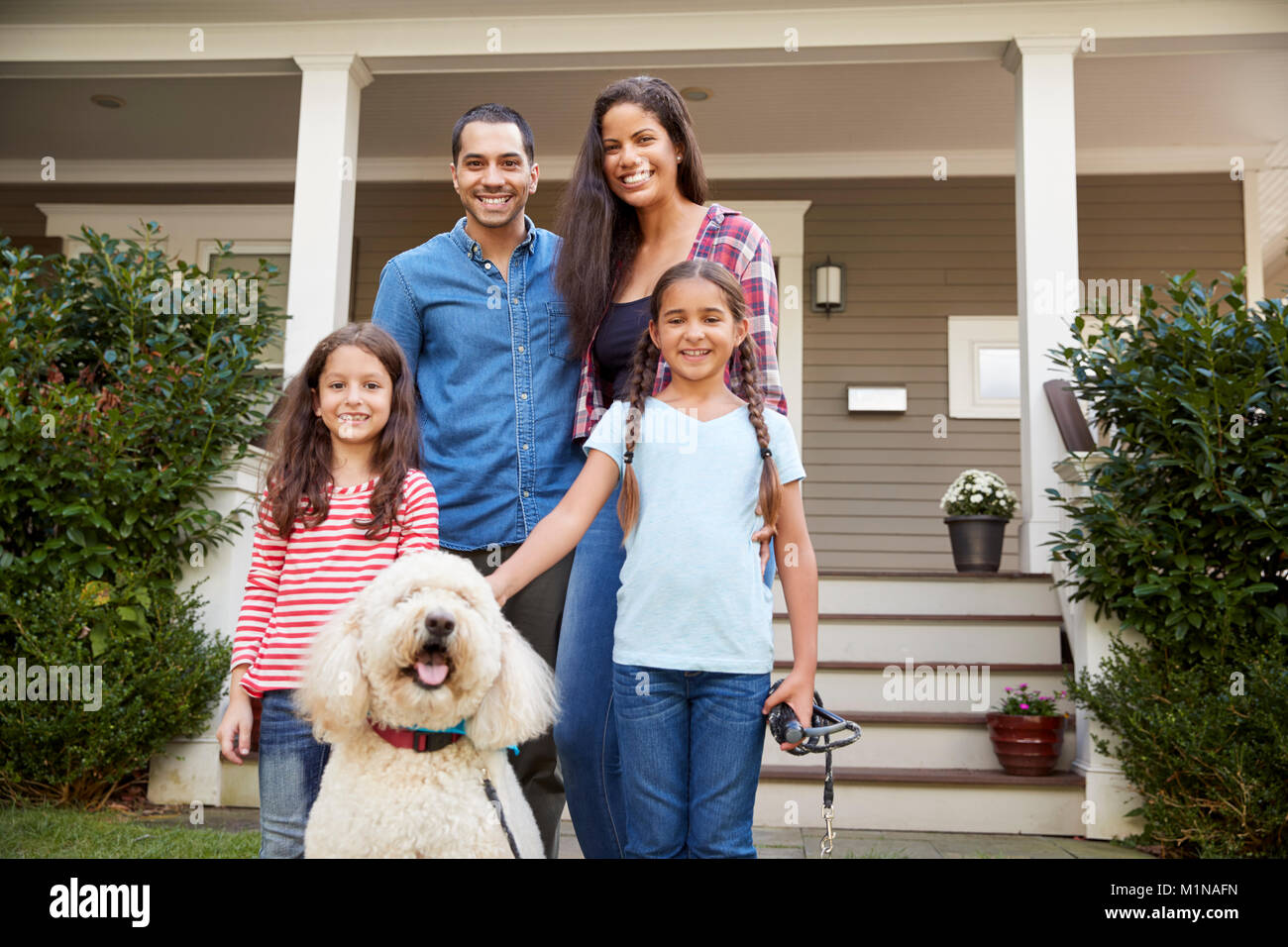 Retrato de familia de pie en frente de la casa con perro Foto de stock