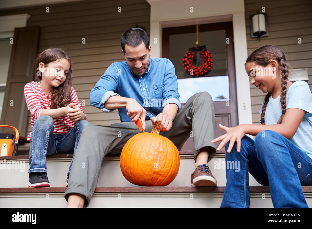 Padre e hijas tallar la calabaza de Halloween en casa pasos Foto de stock