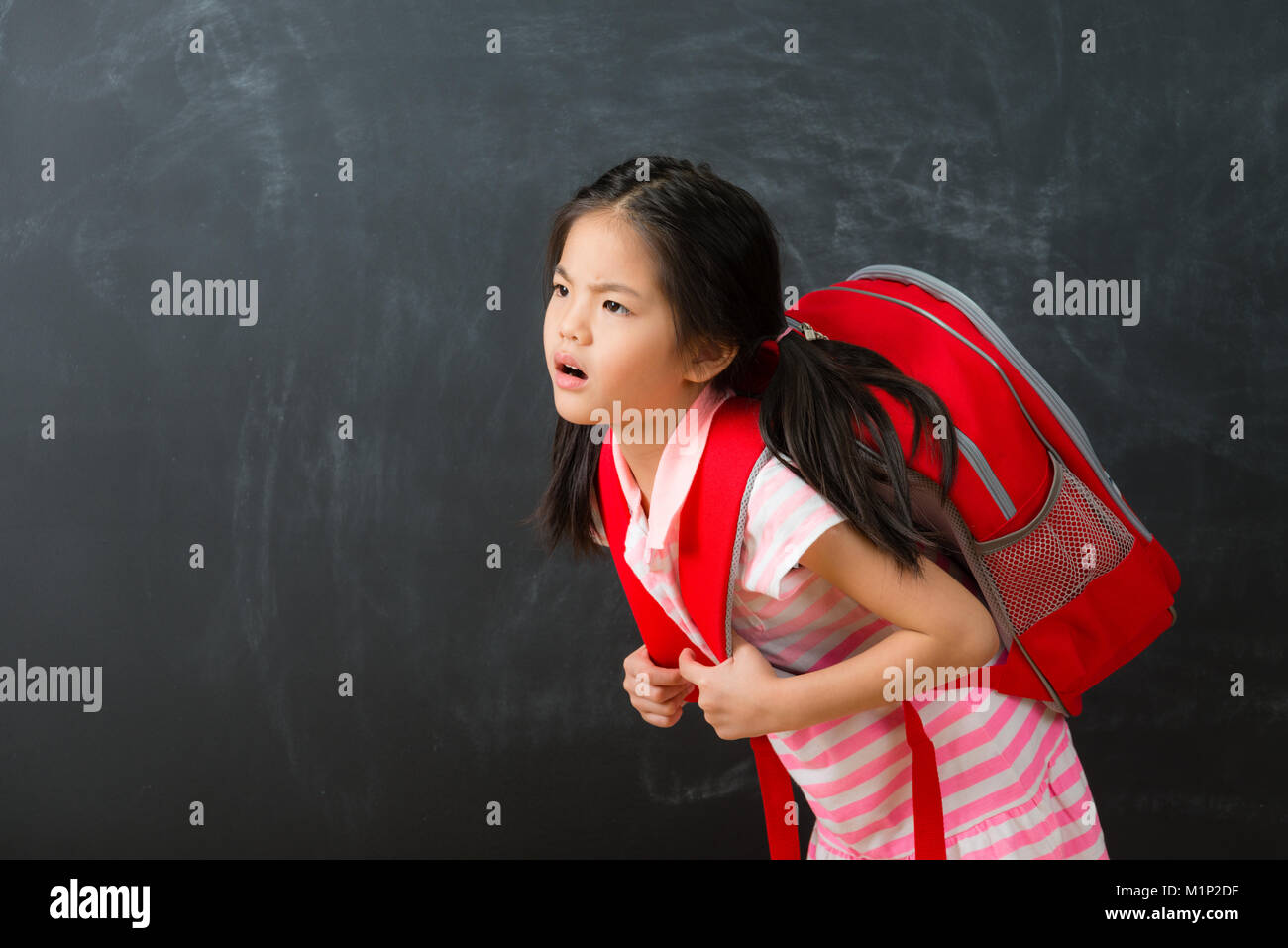 Pequeña niña cargando una pesada mochila escolar Fotografía de stock - Alamy