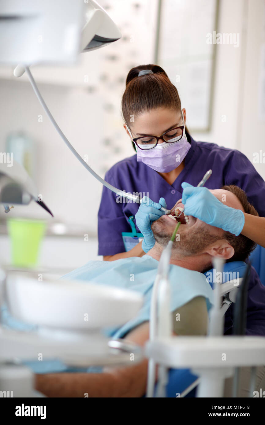 Mujer diente de perforación y resolver problema de salud en la clínica dental Foto de stock