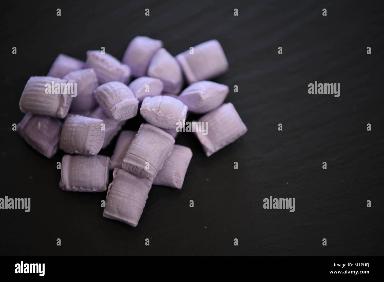 Old Fashioned dulces golosinas o dulces llamados cremas violeta en un color  rosa lila sobre fondo negro Fotografía de stock - Alamy