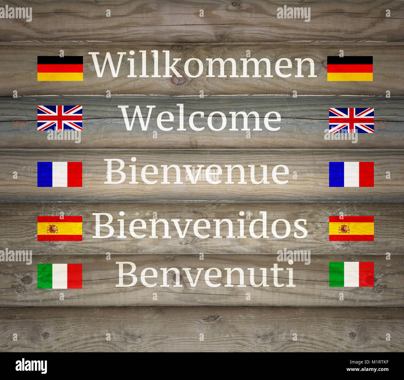 Cartel de madera mostrando bienvenido en cinco idiomas diferentes con sus banderas Foto de stock