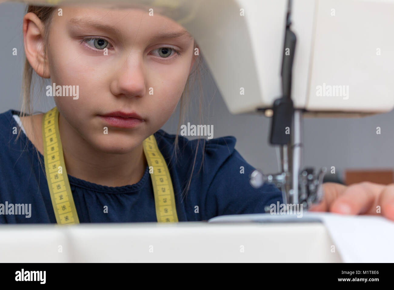 Retrato de una niña de 8 años que es coser con máquina de coser. Foto de stock