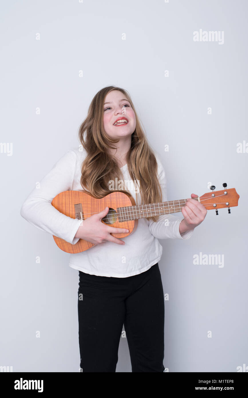 Chica cantando y tocando ukulele sobre fondo blanco Fotografía de stock -  Alamy