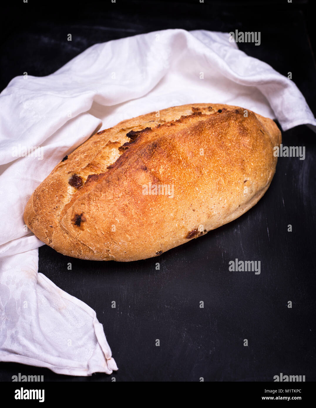 Toda la barra de pan de harina de trigo con pasas de uva blanca sobre un  fondo negro, detrás de una servilleta textil blanco, vista superior  Fotografía de stock - Alamy