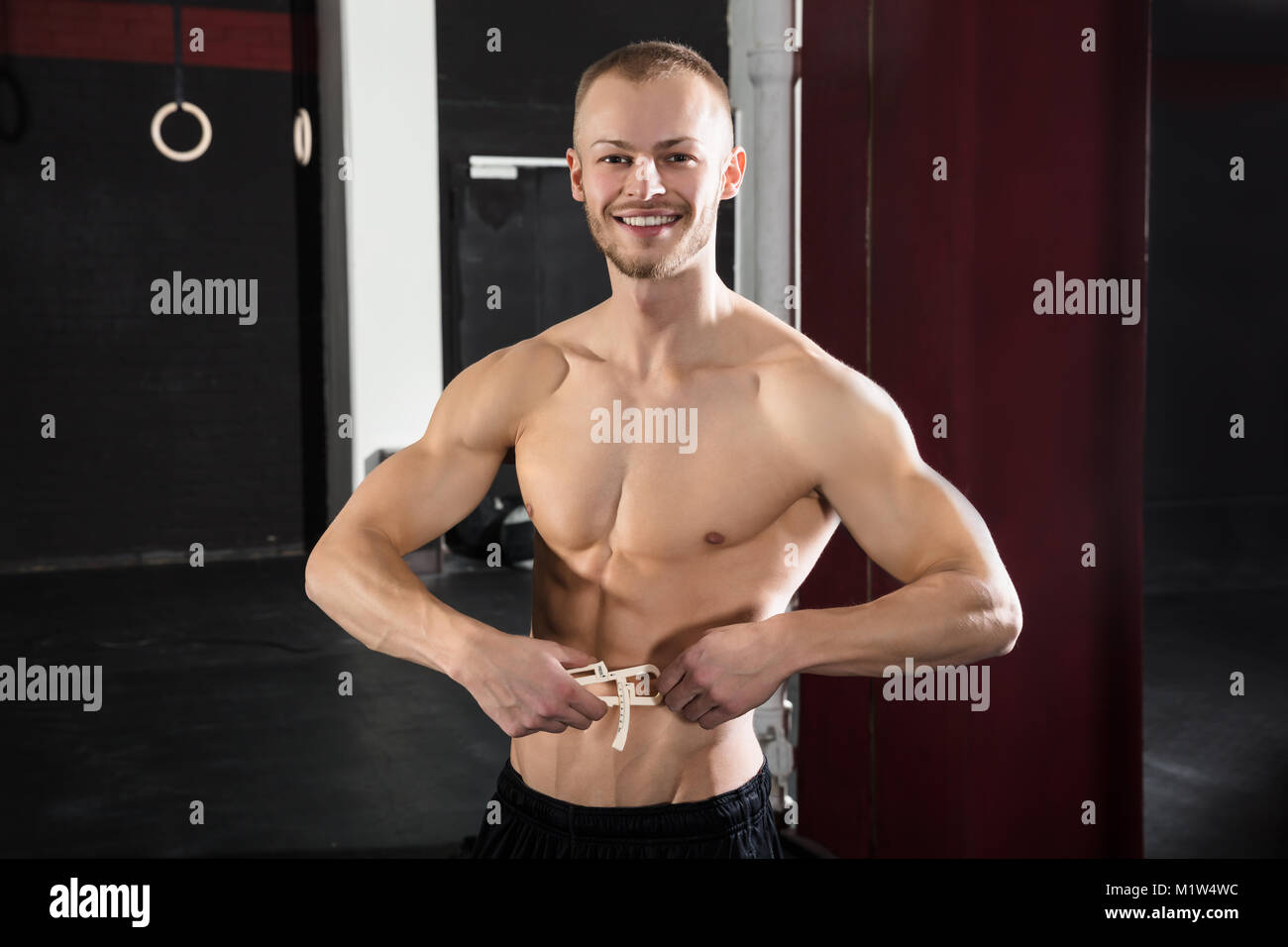 Amplia gama Asentar Que Retrato de un hombre deportista medir su grasa corporal con la mordaza en  el gimnasio Fotografía de stock - Alamy