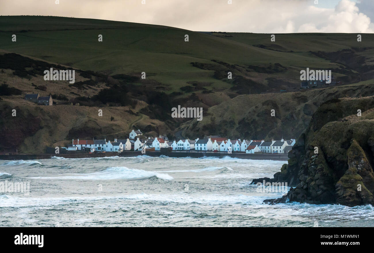 Fuertes vientos crean una oleada en el Mar del Norte a lo largo de la costa noreste de Escocia, con grandes olas hacia una pequeña cala en el pintoresco pueblo de Pennan, Aberdeenshire, Escocia, Reino Unido, famoso por ser un lugar de cine para la película 'local Hero' Foto de stock