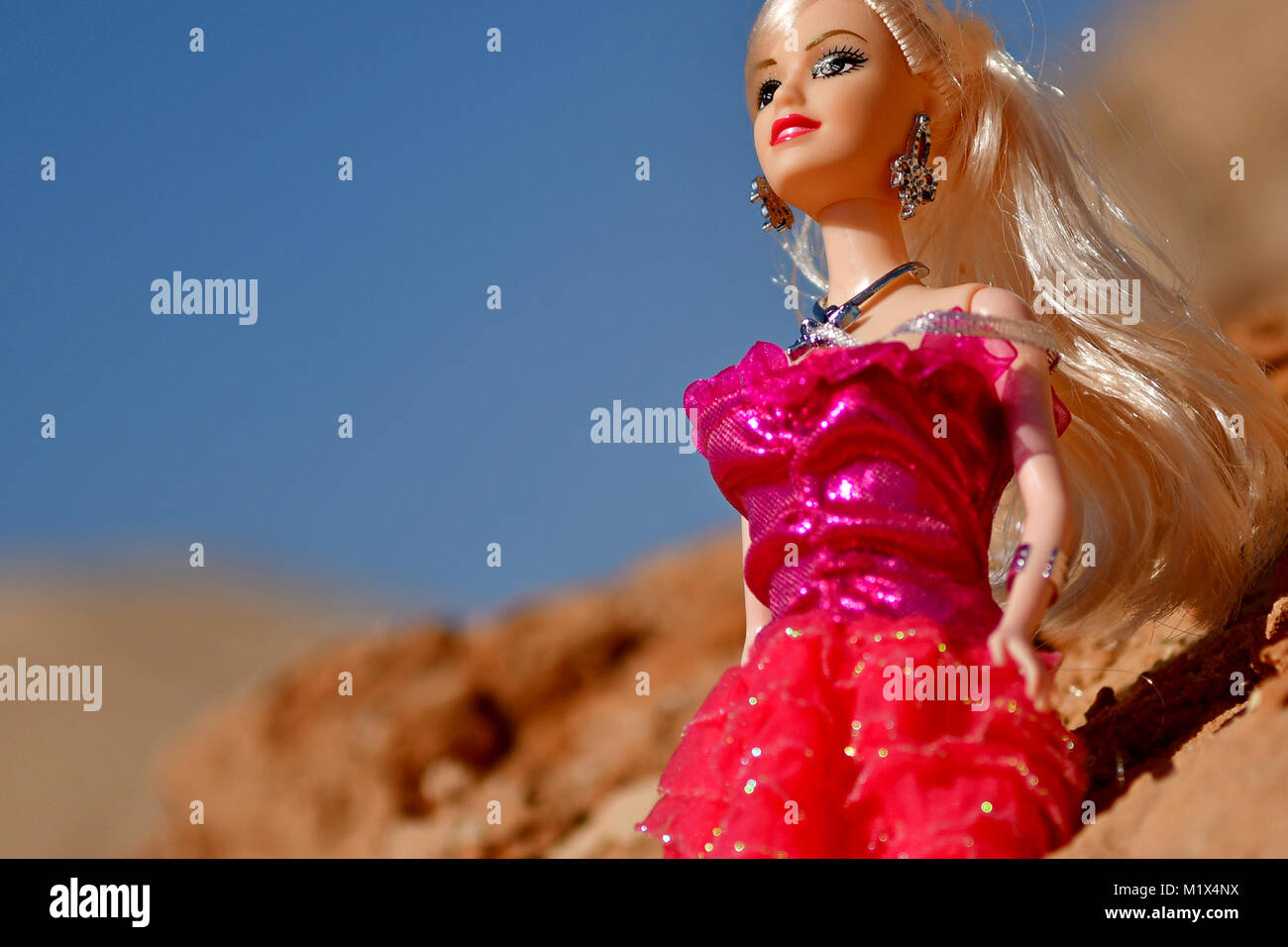 Barbie niñas vestidas de rojo y azul son posar para fotos de modelado en  las rocas del desierto en la ubicación Fotografía de stock - Alamy