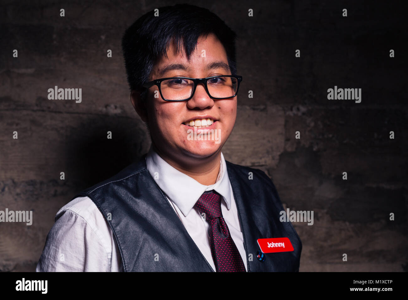 Joven Hombre transgénero en ropa semi formal con un chaleco de cuero estilo  bondage plantea, en un sucio ubicación urbana Fotografía de stock - Alamy