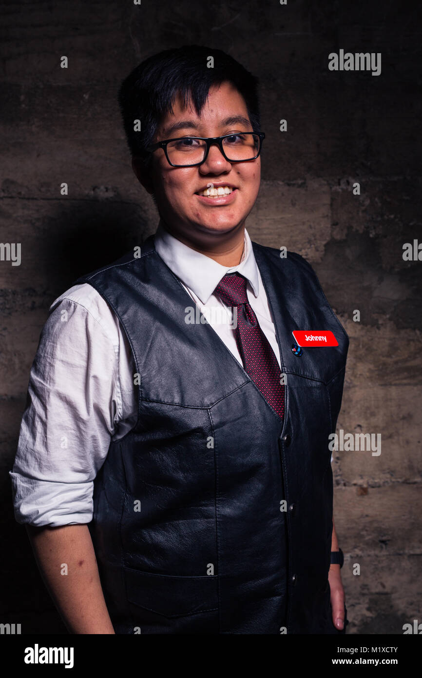 verbo Favor Dependiente Joven Hombre transgénero en ropa semi formal con un chaleco de cuero estilo  bondage plantea, en un sucio ubicación urbana Fotografía de stock - Alamy