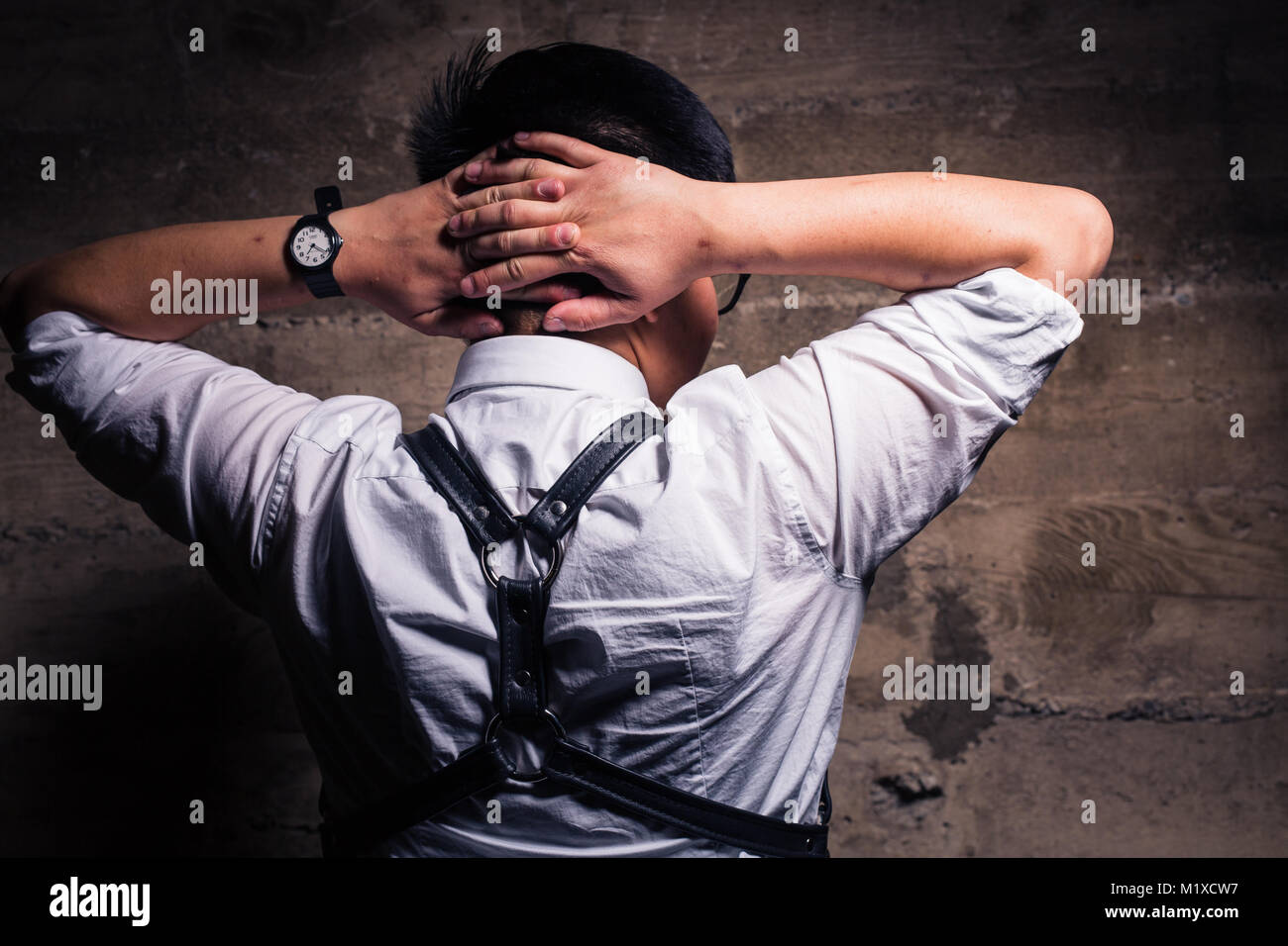 Joven Hombre transgénero en ropa semi formal con un arnés de cuero estilo  bondage plantea, en un sucio ubicación urbana Fotografía de stock - Alamy