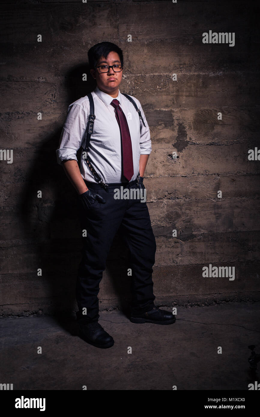 Cortar mineral Leche Joven Hombre transgénero en ropa semi formal con un arnés de cuero estilo  bondage plantea, en un sucio ubicación urbana Fotografía de stock - Alamy