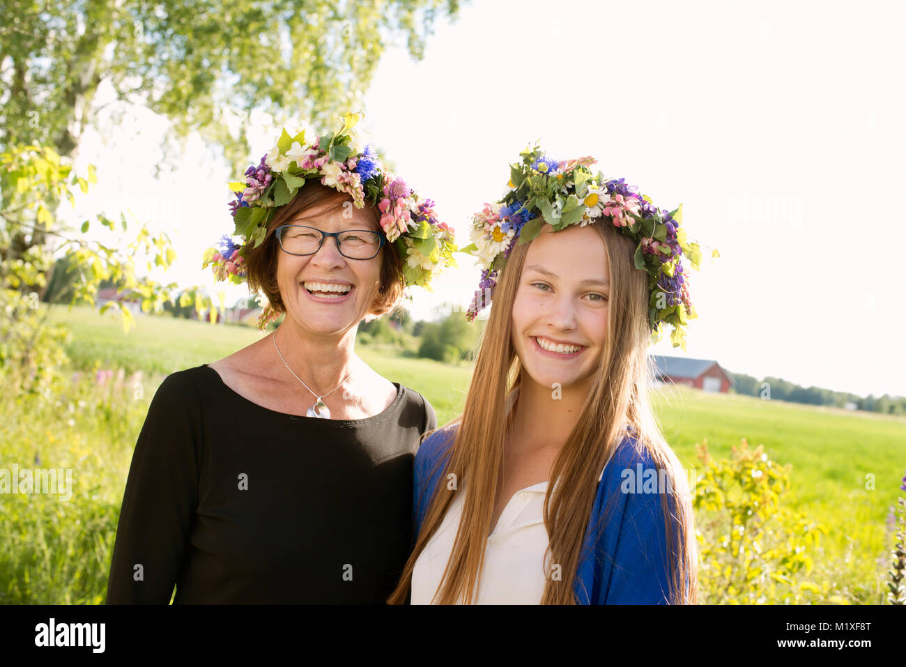 Chica y su abuela vistiendo midsummer coronas en Kallandso, Suecia Foto de stock